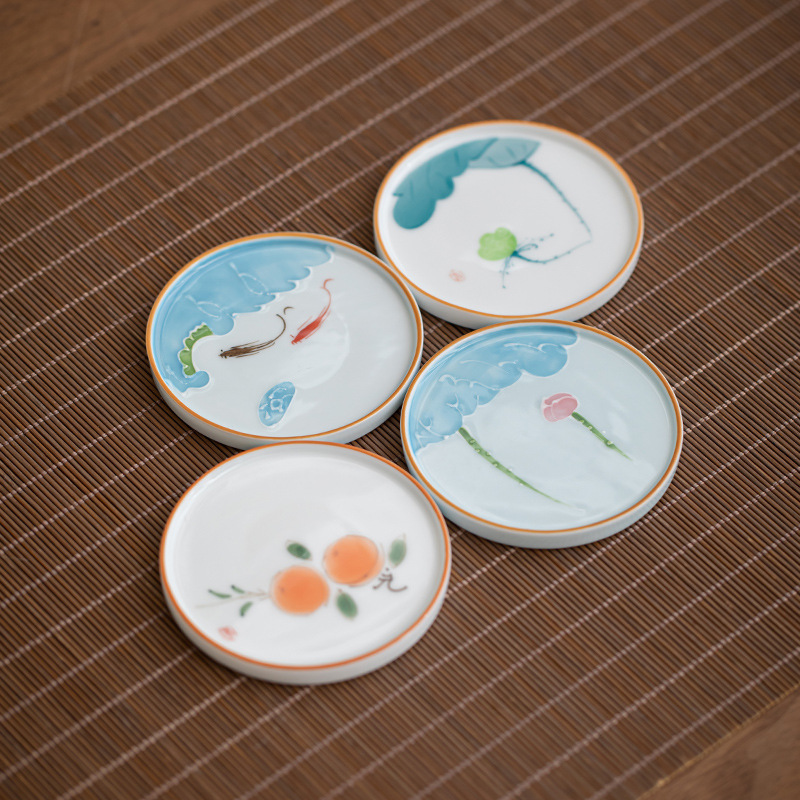 Four ceramic coaster designs featuring fish, flowers and fruit